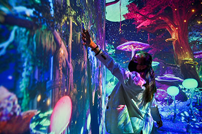 A person touching the walls in a room with immersive underwater images projected onto the walls