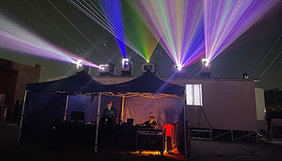 Projector technicians in a tent with projector lights streaming above them