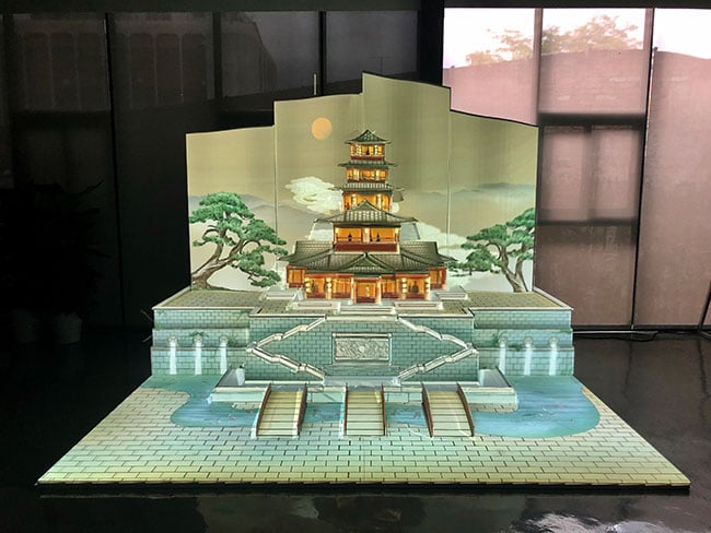 A scale model of a temple with trees on each side sitting on a table.