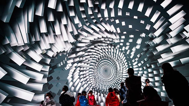 A group of people stand in front of a brightly illuminated 3D image.