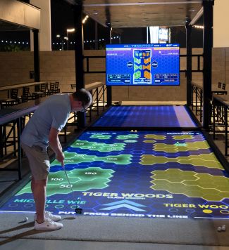 A golfer readies a shot onto a projection mapped putting area.