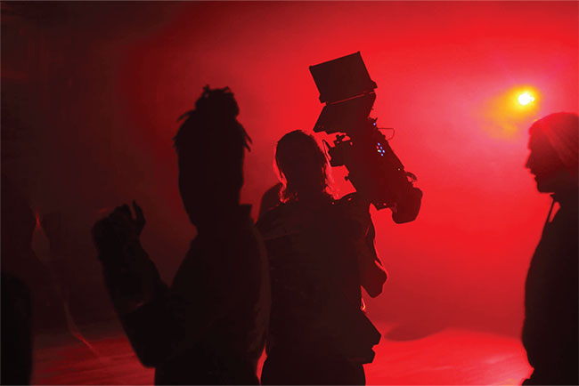 Three people in relief against a red background.