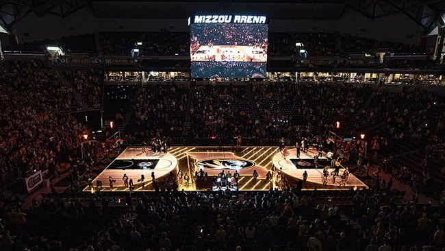 A basketball court is illuminated by projection mapped content.