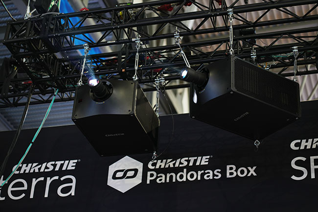 Two RGB pure laser projectors hanging from an overhead truss.