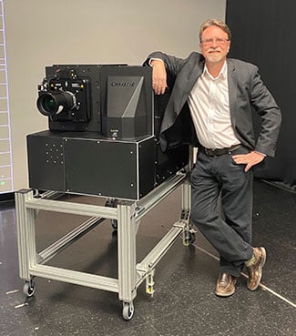 Man rests his arm on the side of a Christie E3LH Dolby Vision Cinema Projection System.