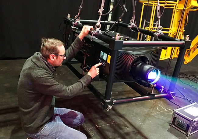 A man pressing a button on the side of a large projector.