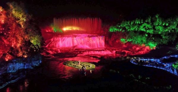 A waterfall is lit up with vibrant colors.