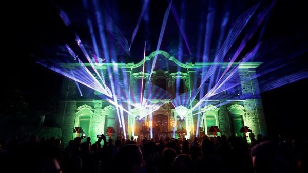 A crowd in front of a brightly illuminated building outside at night.
