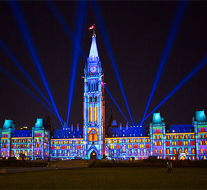 A grand building seen at night, lit up in a colorful pattern using projection mapping.