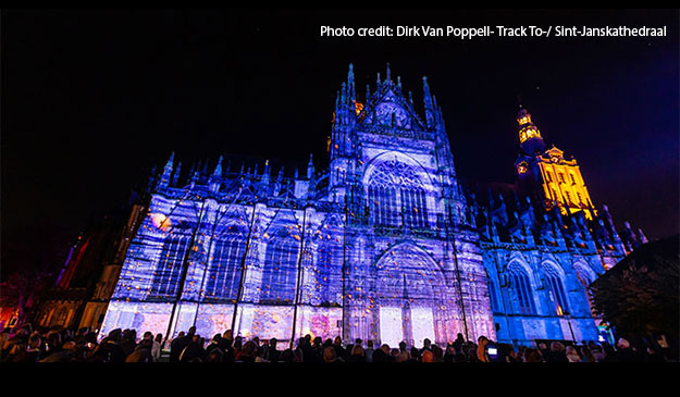 A large gothic chuch seen at night, lit up with patterns projection mapped onto it.